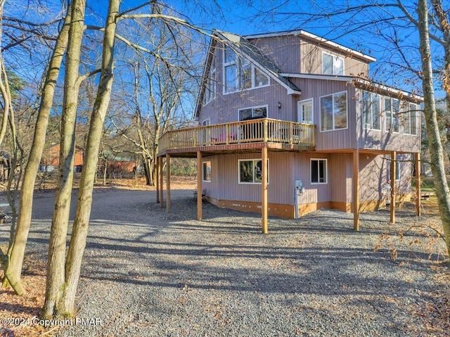 back of property featuring driveway and a wooden deck