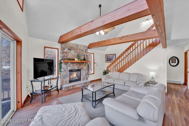 living area with lofted ceiling with beams, wood finished floors, stairs, baseboard heating, and a fireplace