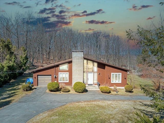 view of front of property featuring a chimney, driveway, and an attached garage