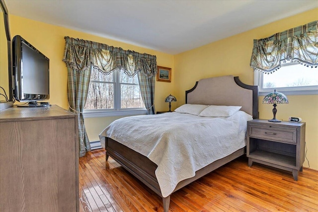 bedroom featuring hardwood / wood-style flooring and a baseboard heating unit