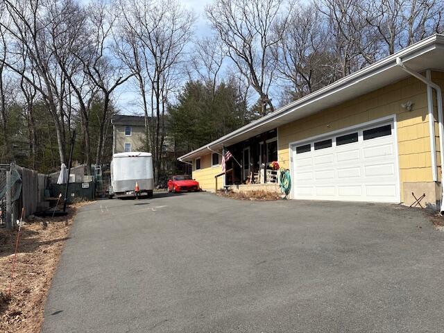 view of home's exterior with aphalt driveway, an attached garage, and fence