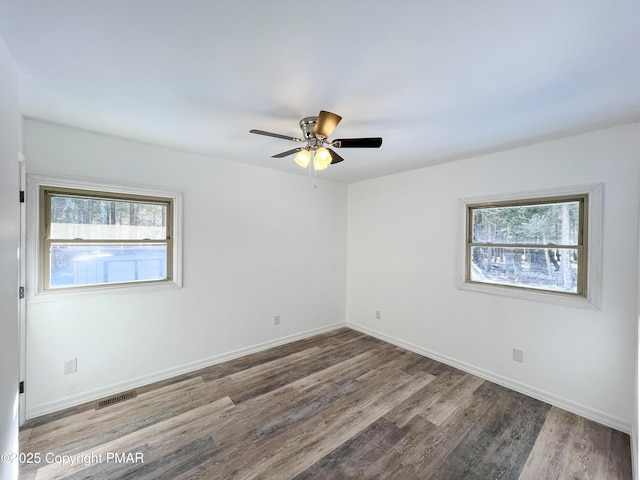 empty room featuring baseboards, visible vents, ceiling fan, and wood finished floors