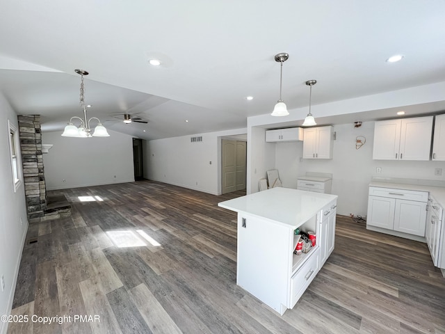 kitchen with wood finished floors, visible vents, white cabinets, hanging light fixtures, and a center island