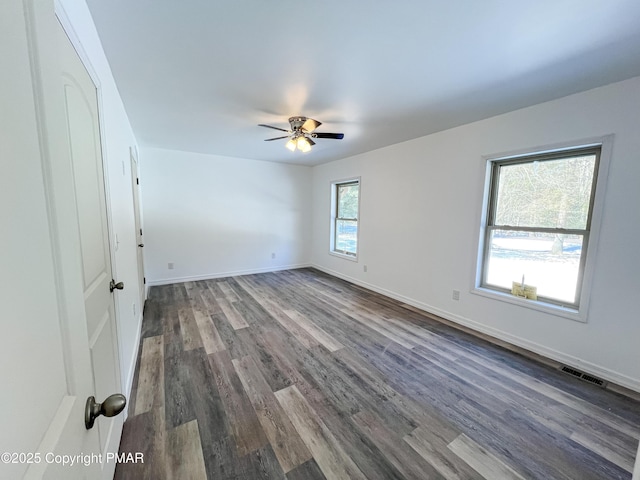 unfurnished room featuring ceiling fan, baseboards, visible vents, and dark wood finished floors