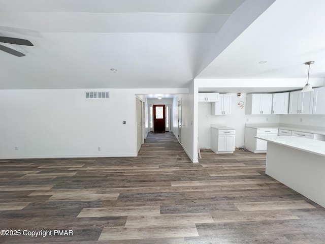 kitchen featuring visible vents, hanging light fixtures, open floor plan, white cabinetry, and wood finished floors