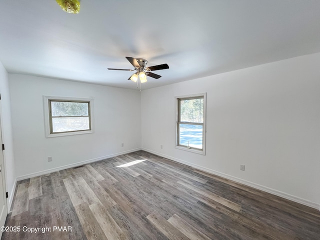 spare room featuring baseboards, ceiling fan, wood finished floors, and a healthy amount of sunlight