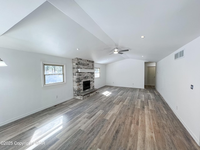 unfurnished living room with a fireplace, lofted ceiling, visible vents, wood finished floors, and baseboards