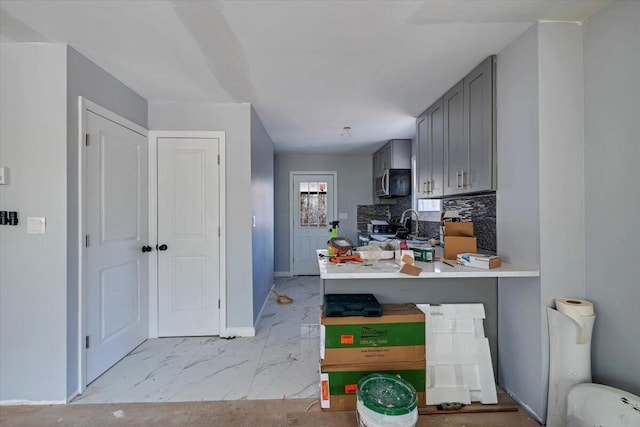 kitchen featuring marble finish floor, gray cabinetry, stainless steel appliances, light countertops, and baseboards