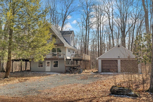 view of home's exterior with stairs, an outbuilding, a deck, and a detached garage