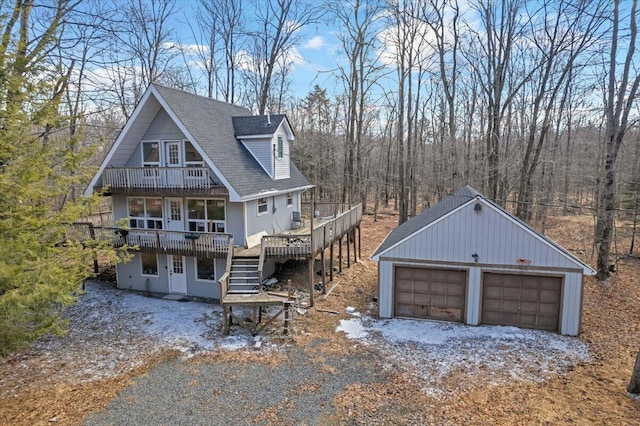 view of front of property with stairway, roof with shingles, a garage, and a deck