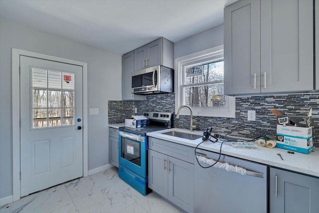 kitchen with marble finish floor, gray cabinets, stainless steel appliances, and a healthy amount of sunlight