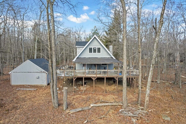 rear view of house with a wooden deck, a chimney, and an outbuilding