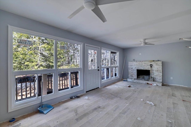 unfurnished living room featuring wood-type flooring, ceiling fan, and a fireplace