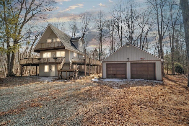 exterior space with stairway, a detached garage, an outdoor structure, and a deck