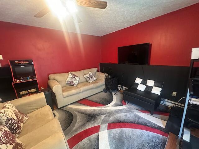 carpeted living area with a textured ceiling and ceiling fan