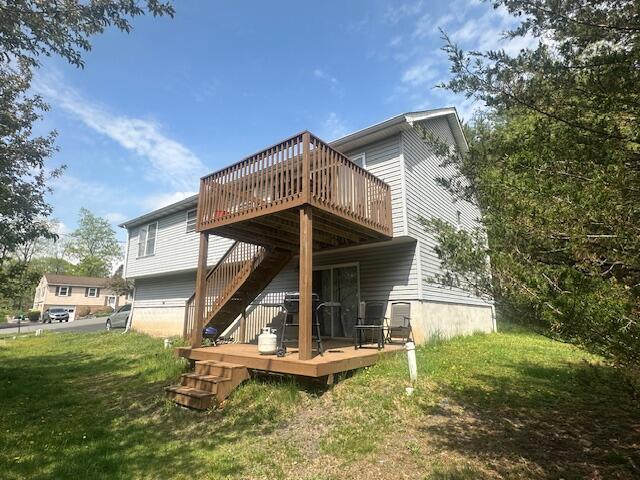 rear view of house featuring a yard, a deck, and stairs