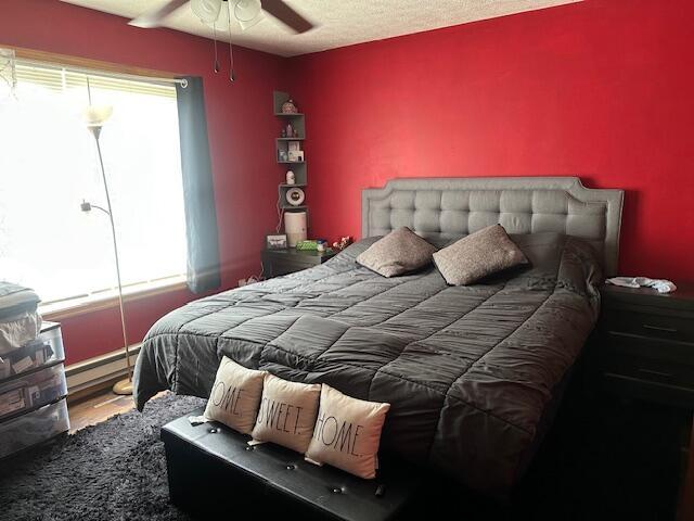bedroom with a ceiling fan and a baseboard radiator