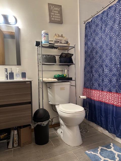 bathroom featuring curtained shower, vanity, and toilet