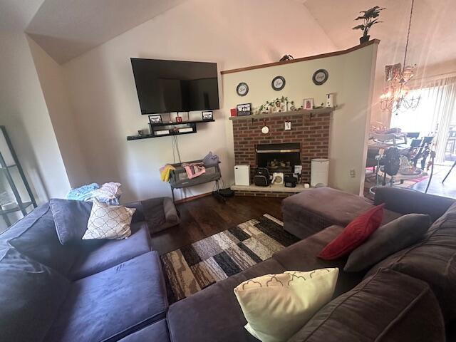 living area featuring lofted ceiling, a brick fireplace, and wood finished floors