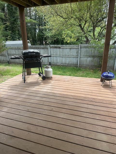 wooden deck with area for grilling and a fenced backyard
