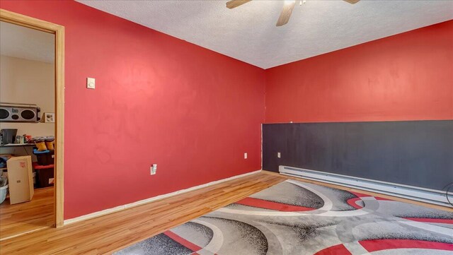 838 Cayuga Way, Stroudsburg, PA 18360 - bedroom featuring wood finished floors, a textured ceiling, a baseboard heating unit, and ceiling fan