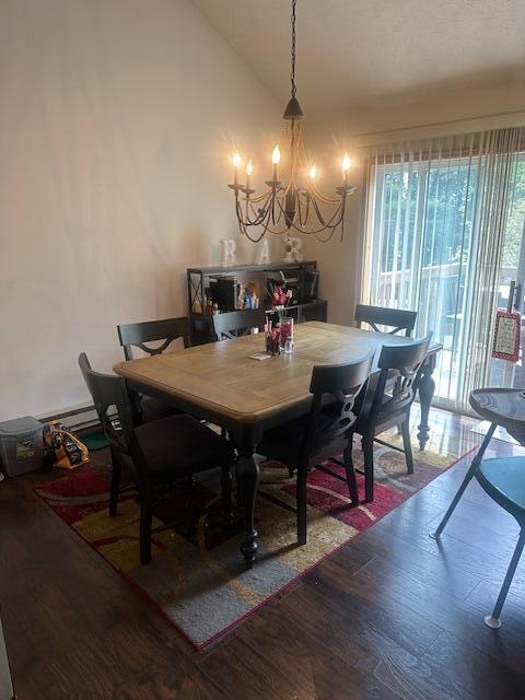 dining area featuring vaulted ceiling, a notable chandelier, and wood finished floors