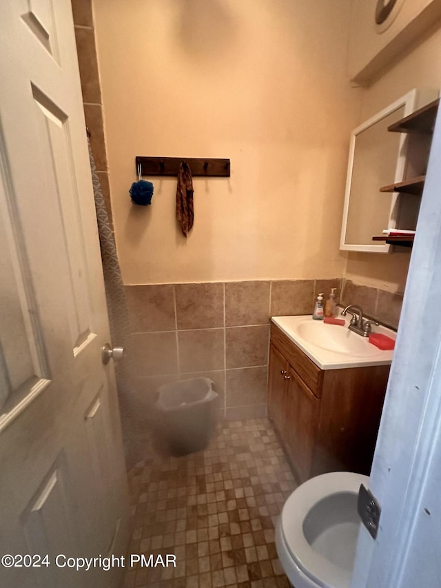 half bath featuring a wainscoted wall, tile walls, toilet, and vanity