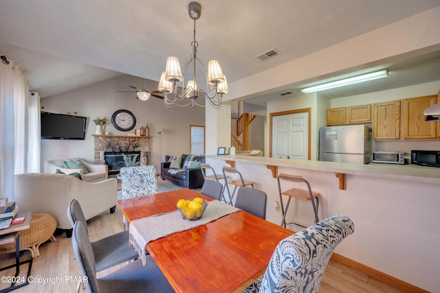 480 Spruce Dr, Tannersville, PA 18372 - dining space featuring light wood-style floors, a chandelier, a stone fireplace, lofted ceiling, and baseboards