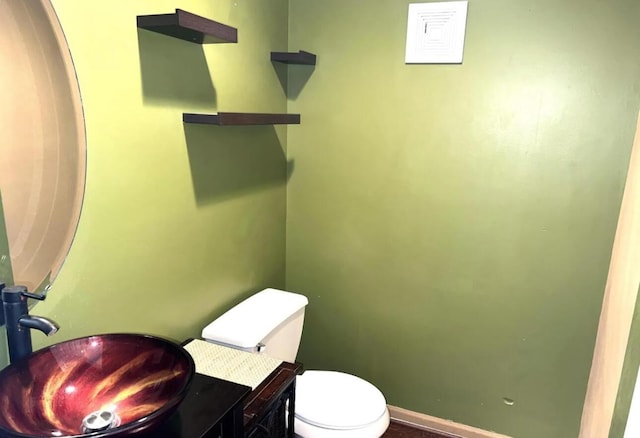 bathroom featuring a sink, baseboards, and toilet