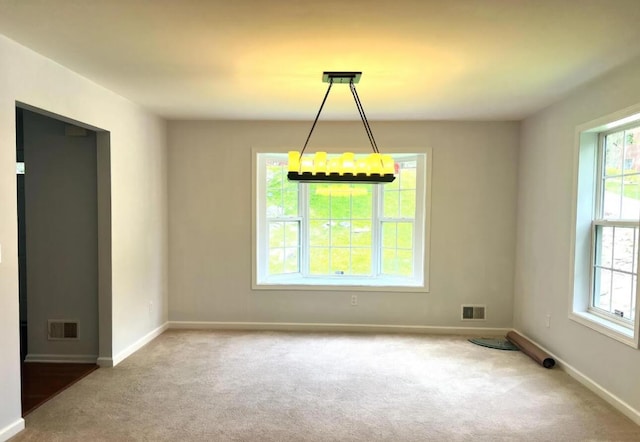 carpeted empty room with baseboards, visible vents, and a wealth of natural light