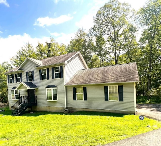 colonial home with a front lawn and roof with shingles