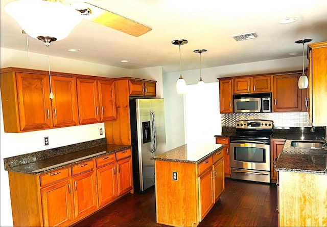 kitchen with visible vents, a center island, appliances with stainless steel finishes, dark wood-style floors, and a sink