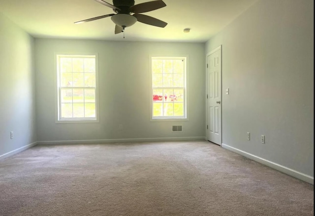 unfurnished room featuring visible vents, a healthy amount of sunlight, baseboards, and carpet