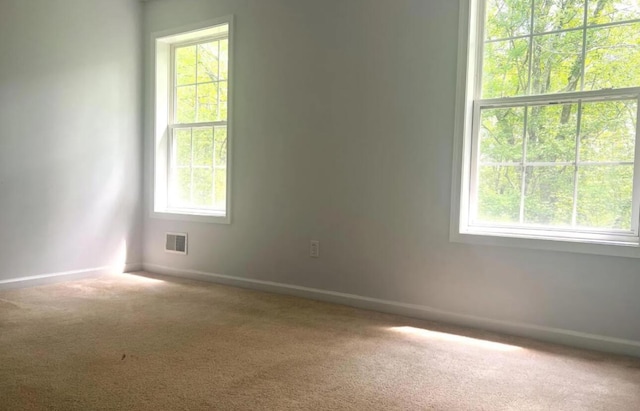 carpeted empty room featuring visible vents and baseboards