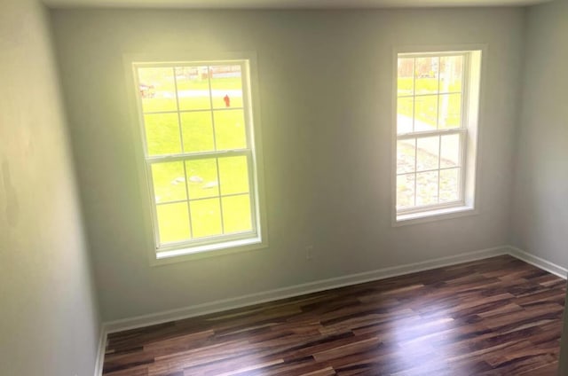 spare room featuring baseboards and dark wood-style flooring