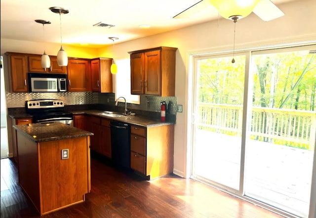 kitchen with visible vents, dark wood finished floors, a sink, stainless steel appliances, and backsplash