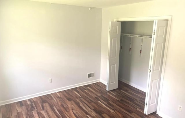 unfurnished bedroom with visible vents, baseboards, a closet, and dark wood-style floors