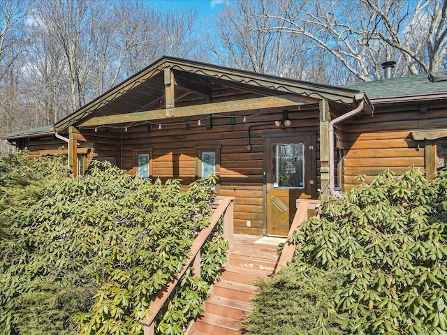 view of front of home with log siding and a shingled roof