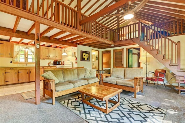 living room with a towering ceiling, light tile patterned floors, stairs, ceiling fan, and light colored carpet