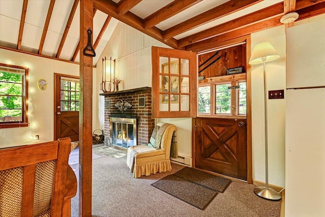 interior space with a wealth of natural light, a fireplace, carpet flooring, and vaulted ceiling with beams