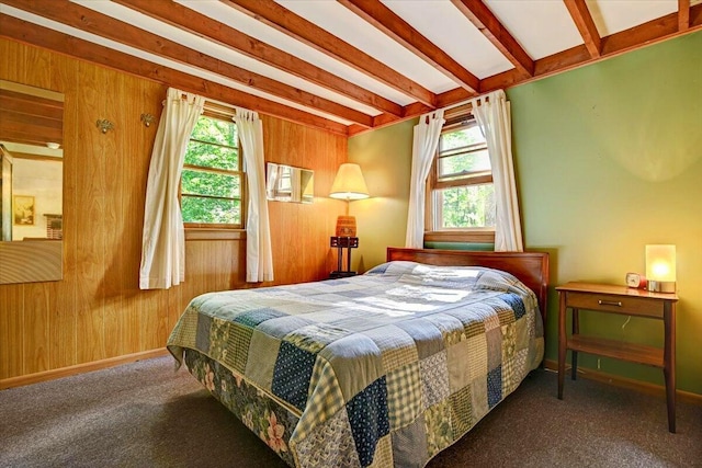 bedroom featuring beamed ceiling, baseboards, carpet flooring, and wood walls