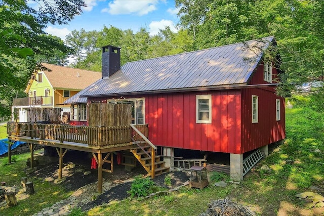 back of property with metal roof, a deck, and a chimney