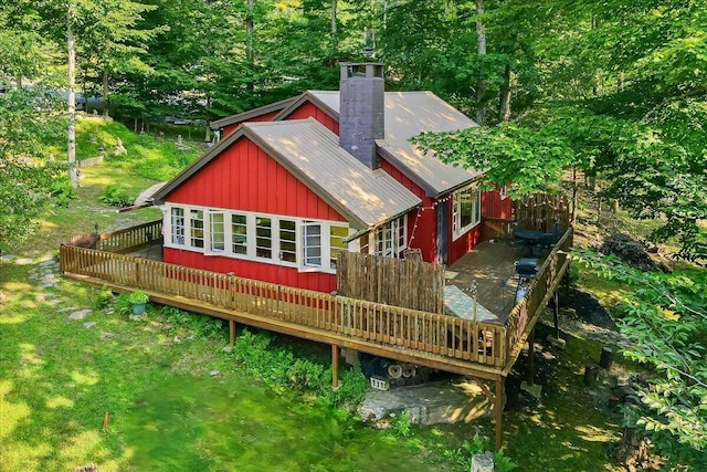 back of property with a yard, a deck, a chimney, and metal roof