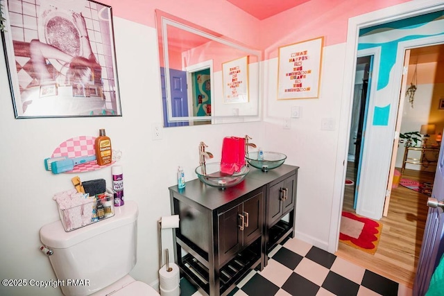 bathroom featuring tile patterned floors, toilet, double vanity, and a sink