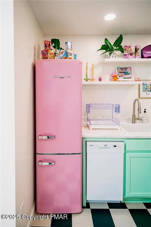 kitchen featuring light floors, white dishwasher, freestanding refrigerator, a sink, and light countertops