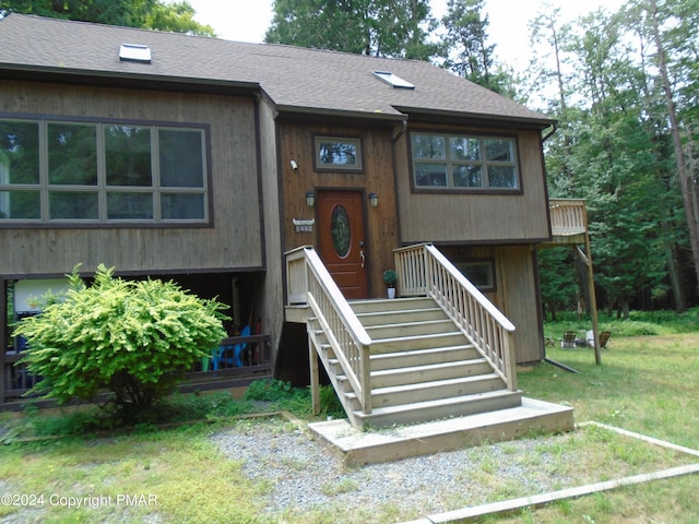 view of front of home featuring a shingled roof and a front yard