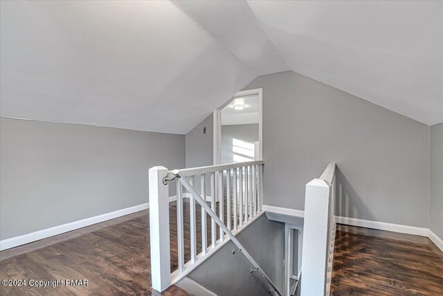 interior space featuring lofted ceiling, wood finished floors, an upstairs landing, and baseboards