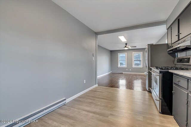 kitchen featuring baseboards, ceiling fan, appliances with stainless steel finishes, baseboard heating, and light wood-style floors