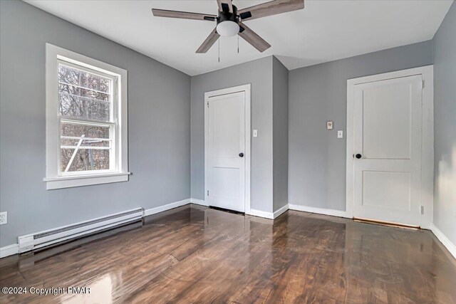 unfurnished room featuring a ceiling fan, baseboards, a baseboard heating unit, and wood finished floors