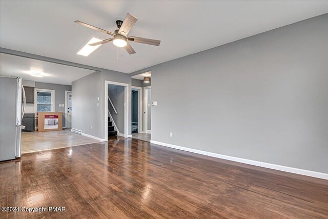 empty room with ceiling fan, baseboards, and wood finished floors